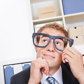 Pensive business man in office with nerd glasses looking up